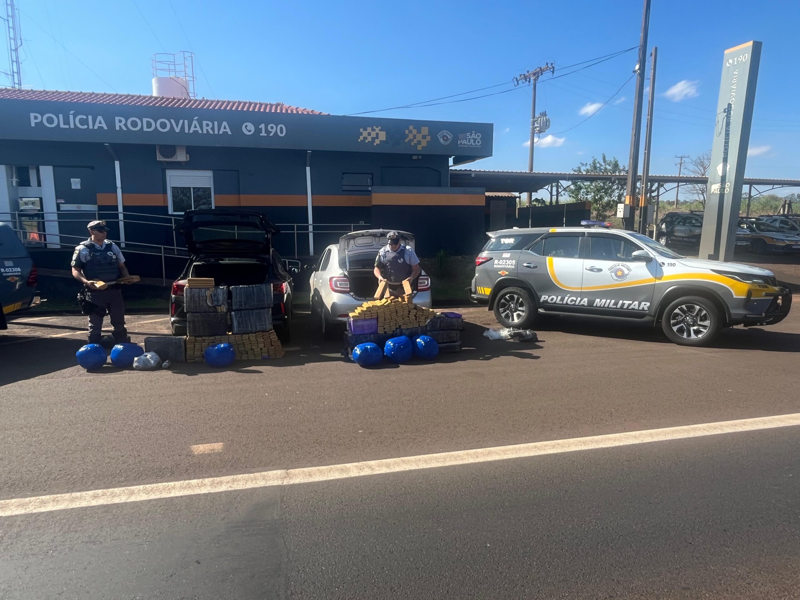 Policiais com materiais apreendidos na estrada.